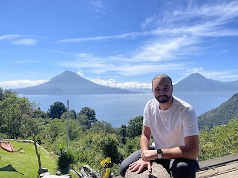 Thomas Bertrand assis au-dessus du lac Atitlán, les volcans Tolimán et San Pedro de l'autre côté de l'eau