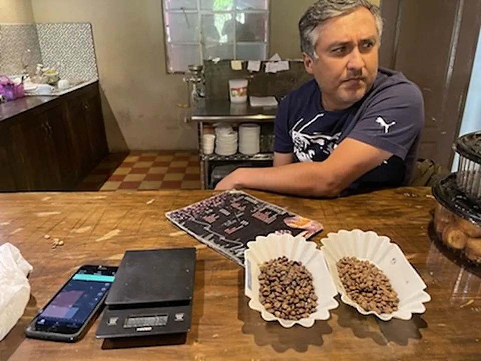 Deux coupelles de café torréfié échantillon sur une table en bois, avec une balance de précision et un téléphone