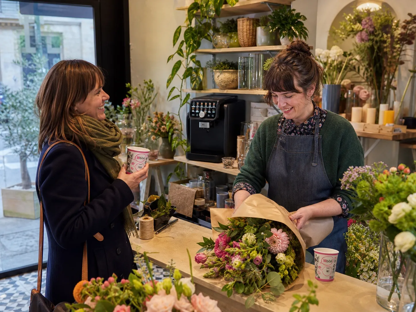 Une fleuriste accueille sa cliente avec des gobelets Bibal Gisèle, la Parvus visible en boutique
